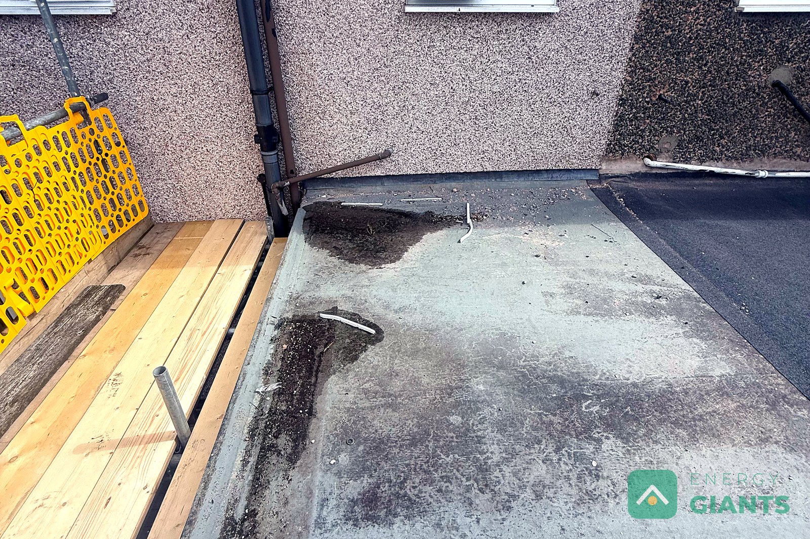 The old felt roof over the rear extension in Llanrwst, stained and holding water, with the scaffold edge protection in place