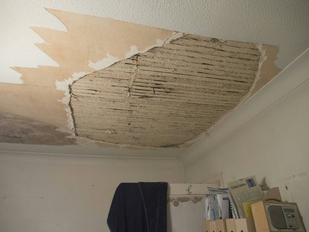 A ceiling with plaster fallen away after a roof leak