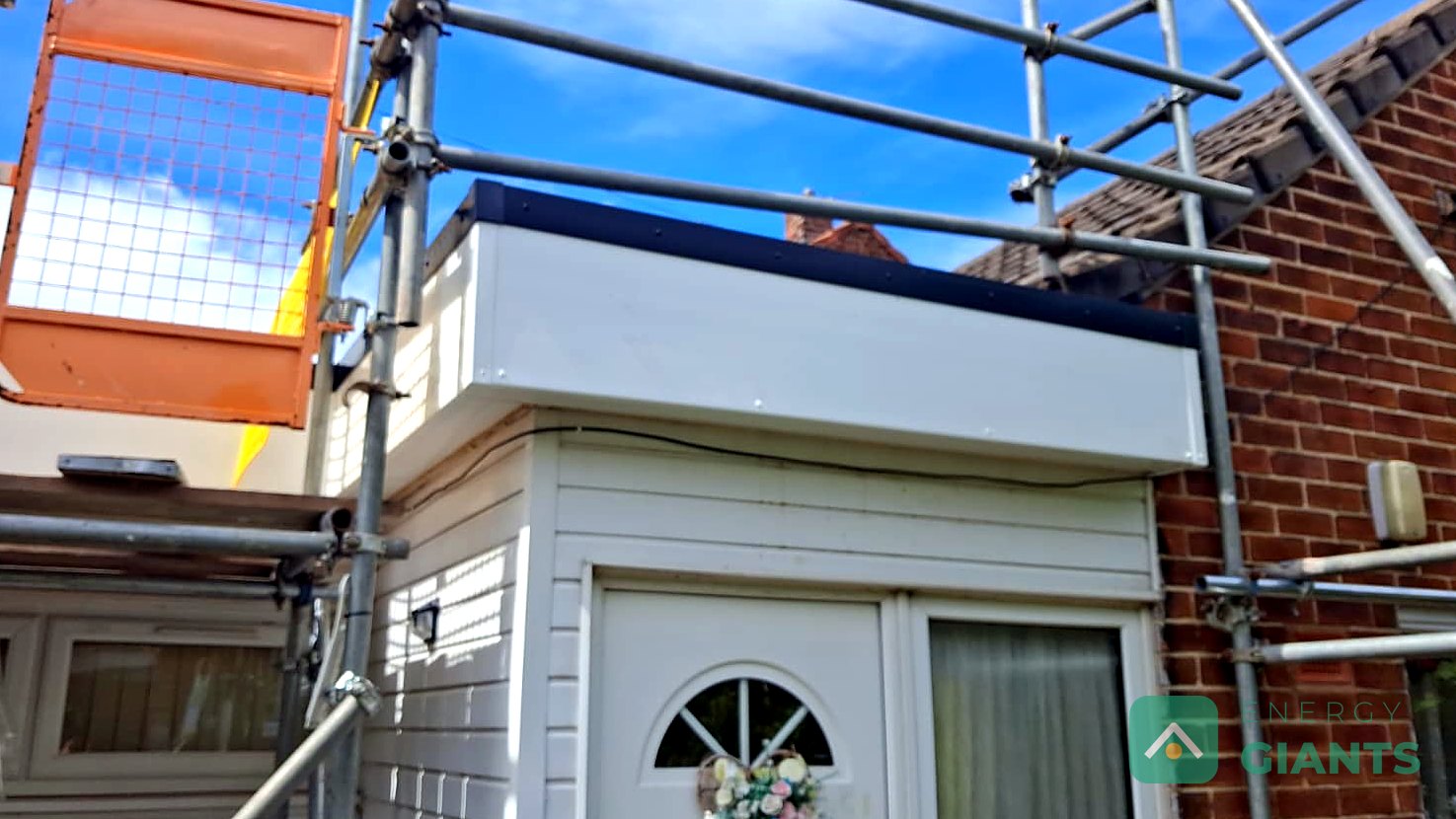 The rear extension in Litherland with its new white fascia box and trims fitted to match the cladding, scaffold still up under a blue sky