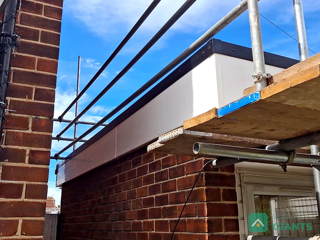 The corner of the new white fascia box on the extension roof in Litherland, seen from the scaffold against a blue sky