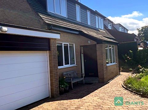 The front of the detached house with its dormers and driveway, before the install