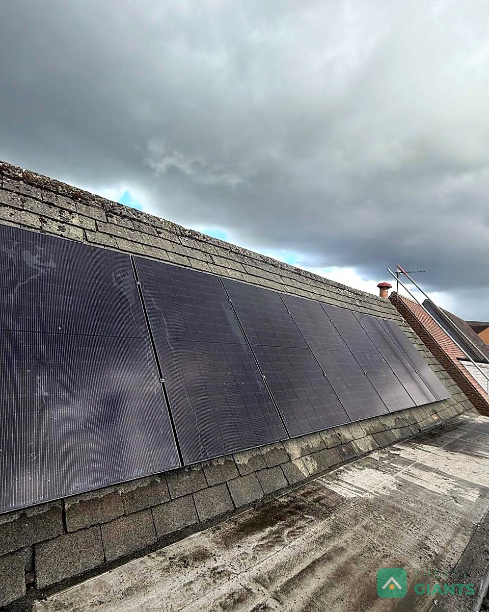 The finished row of seven black panels on the grey tiled roof, seen from the scaffold