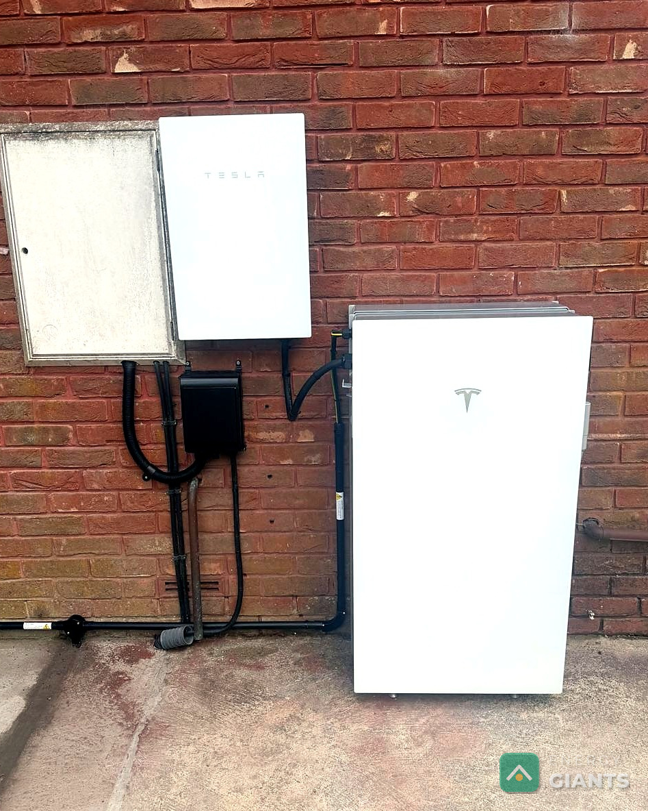 Tesla Powerwall 3 mounted on the outside brick wall of the house beside its isolator enclosure