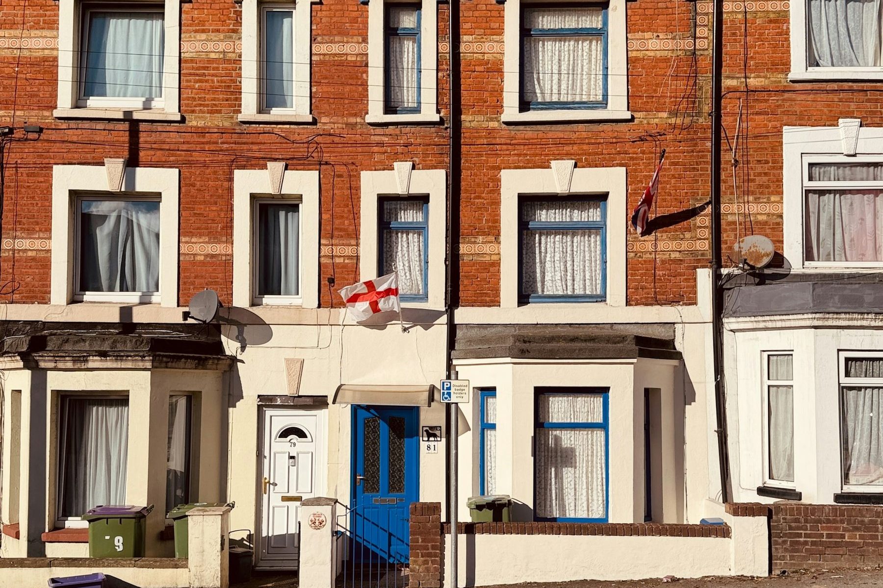 Terraced houses with brick fronts and blue doors. Illustrative image