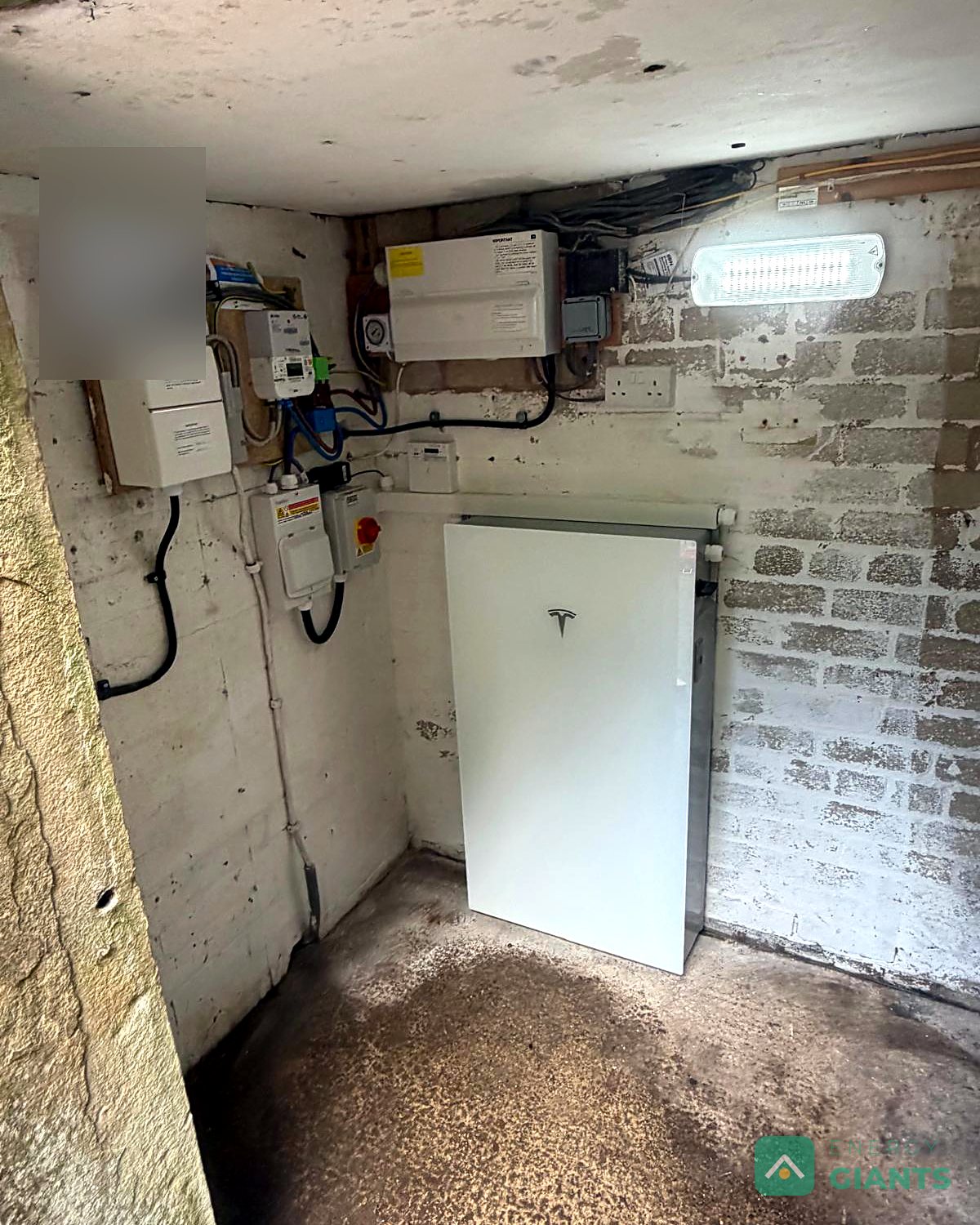 The Tesla Powerwall 3 on the wall of a whitewashed outbuilding with new electrics beside it
