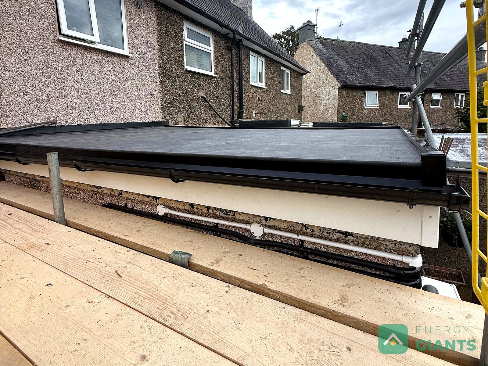 The EPDM membrane dressed down over a new white edge trim at the eaves of the extension roof