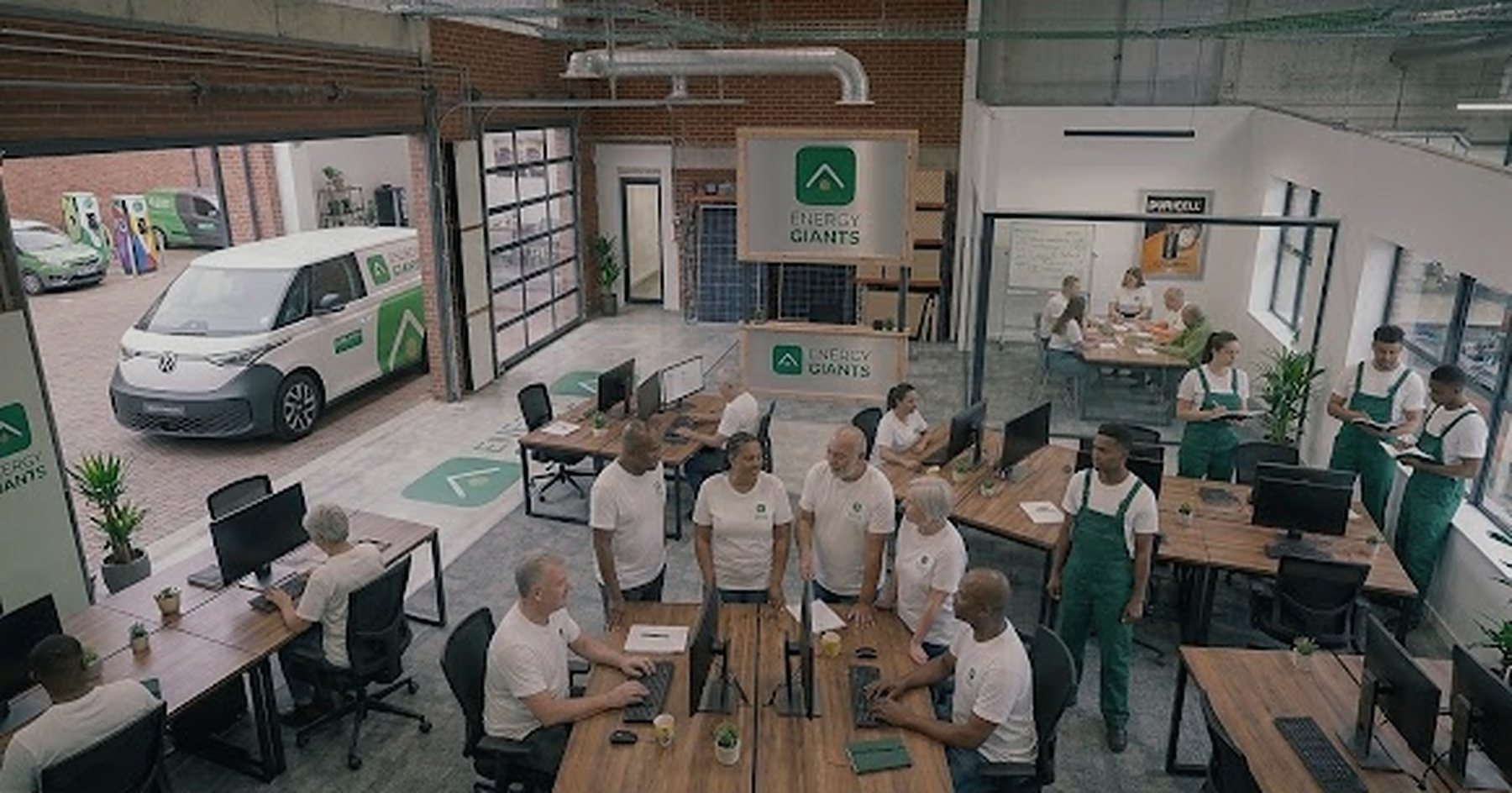 The Energy Giants office: the team at desks under the Energy Giants sign, with a branded van in the loading bay