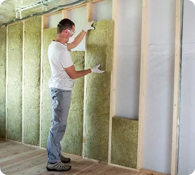 Installer fitting insulation panels to an internal wall
