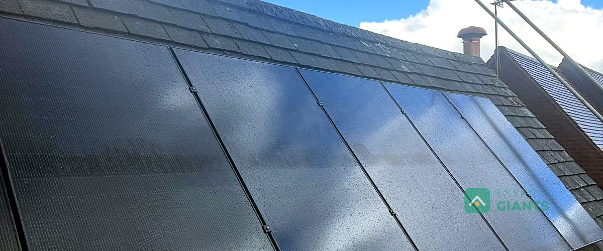 A row of seven black solar panels above the dormers of a detached house in Clitheroe